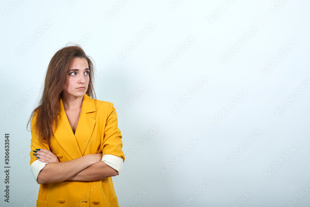 Angry caucasian woman looking aside, holding hands crossed isolated on gray background in studio in yellow jacket. People sincere emotions, lifestyle concept. Angry caucasian woman looking aside, holding hands crossed isolated on gray background in studio in yellow jacket. People sincere emotions, lifestyle concept.