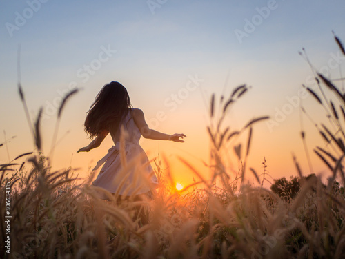 Trendy girl in stylish summer dress feeling free in the field with flowers in sunshine.
