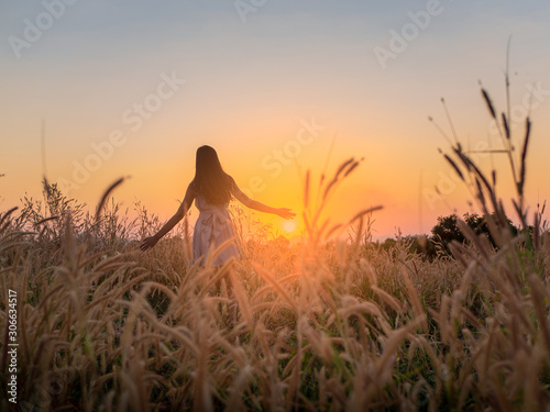 Trendy girl in stylish summer dress feeling free in the field with flowers in sunshine.