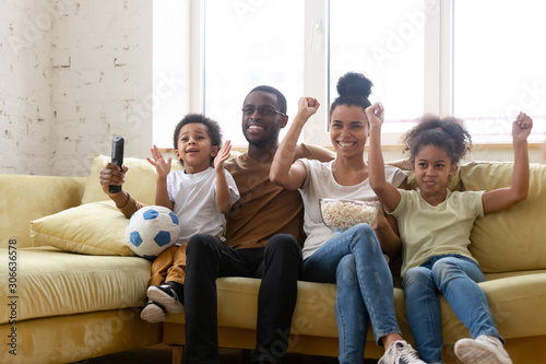 Happy biracial family with kids watch football at home together