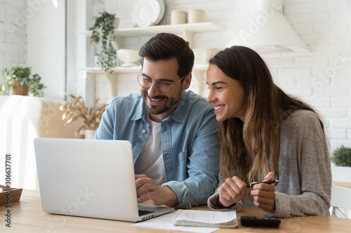 Happy young couple paying bills online in computer app photo