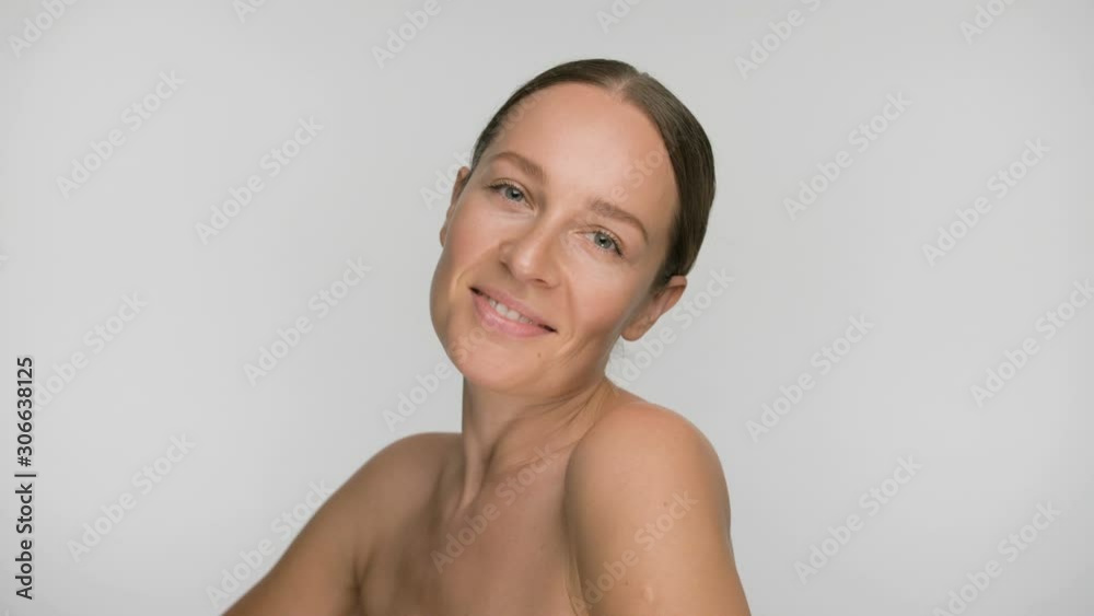 Close-up beauty portrait of young woman with smooth healthy skin, she is smiling beautifully while looking at the camera on white background Close-up beauty portrait of young woman with smooth healthy skin, she is smiling beautifully while looking at the camera on white background
