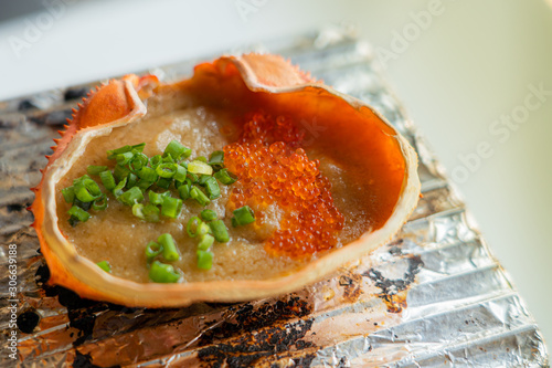 Kani miso. Japanese Kani Miso crabmeat with soybean paste grilled in crab shell at traditional Japanese restaurant. Close up and selective focus. Chacoal grill.