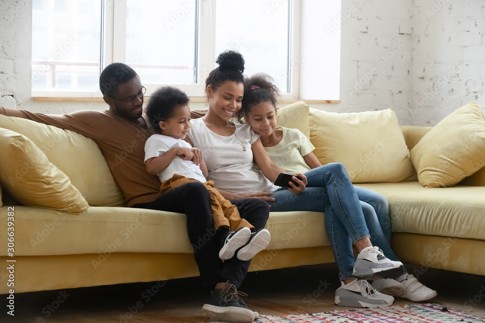 Happy biracial family with kids using cellphone together Happy biracial family with kids using cellphone together