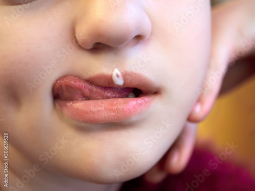 european child with tongue licks the cream from her lip. close up.