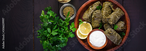 Dolma. Stuffed grape leaves with rice and meat on dark table. Middle eastern cuisine. Top view, overhead, banner photo