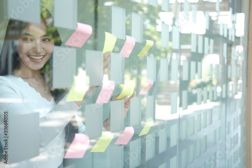 businesswoman woman thinking planning with adhesive notes on glass wall