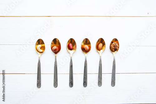 Nuts in spoon on white wooden table with clipping path