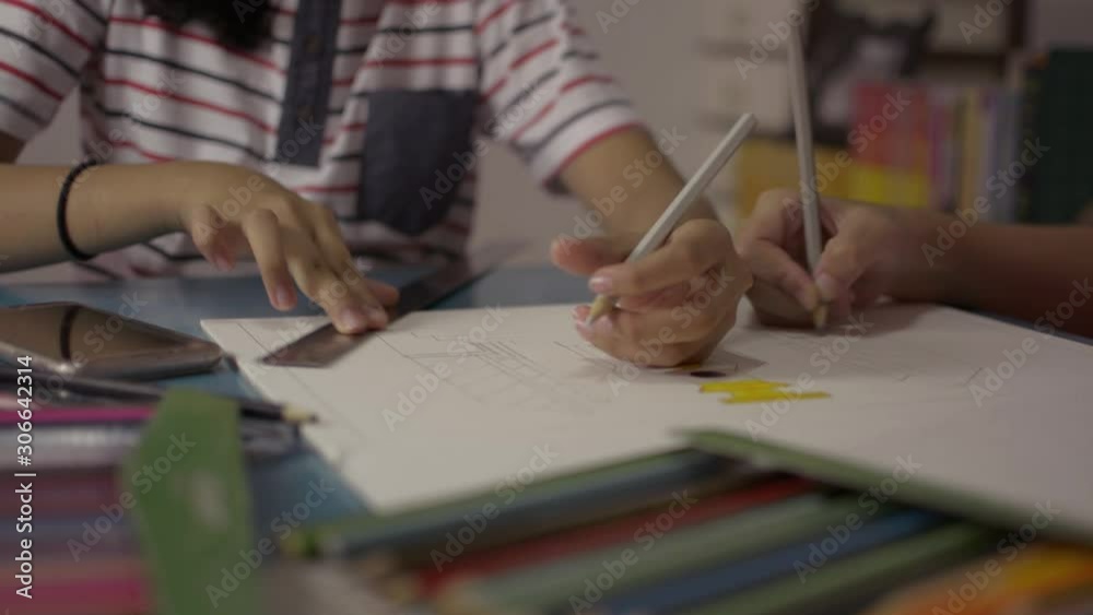 Two girls drawing on a paper and helping each other do homework on the desk at home. Education concept. Two girls drawing on a paper and helping each other do homework on the desk at home. Education concept.