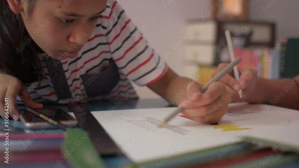 Two girls drawing on a paper and helping each other do homework on the desk at home. Education concept. Two girls drawing on a paper and helping each other do homework on the desk at home. Education concept.