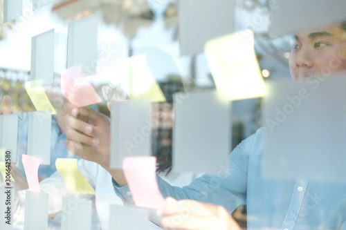 business people working planning discussing idea with sticky reminder note on glass wall