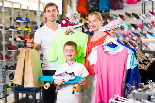 Cheerful mature parents with boy in sport store