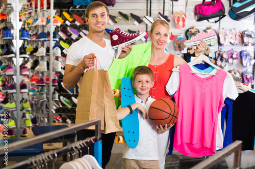 Smiling friendly parents with boy in sport store