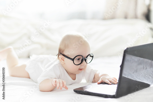 Foto A newborn baby is lying on a soft bed in glasses.