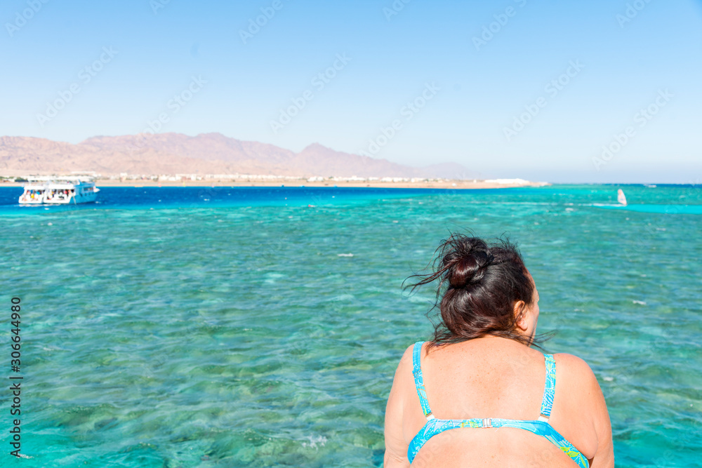 Elderly woman in a swimsuit on a sea vacation on the background of the sea and mountains