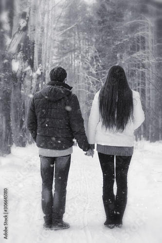 A loving couple on a winter walk. Man and woman on a date in the park in winter. Friends in a winter park © alexkich