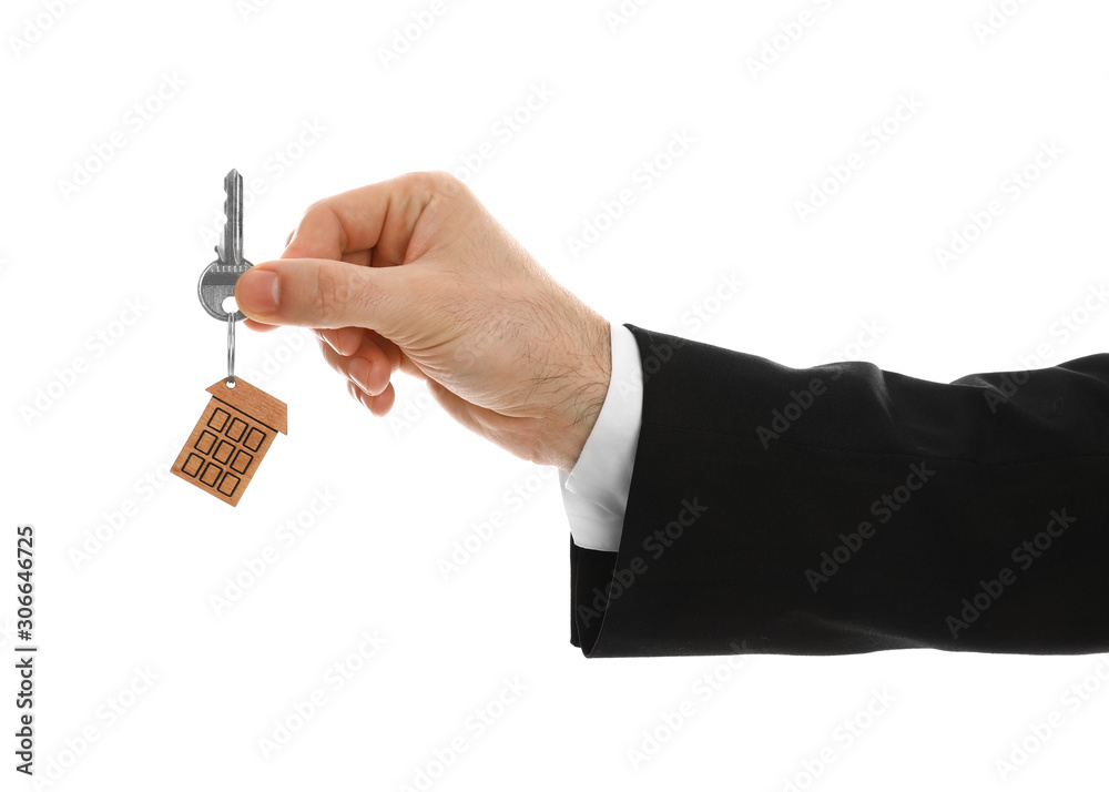 Obraz premium Real estate agent holding house key with trinket on white background, closeup
