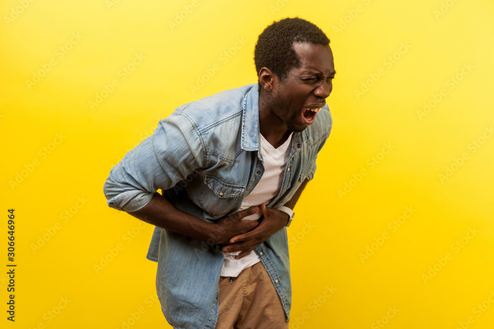 portrait-of-sick-man-in-denim-shirt-hunching-and-grimacing-from-strong