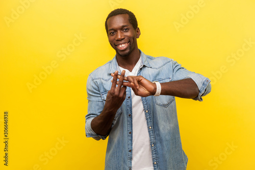 Hashtag symbol. Portrait of friendly joyful man in denim shirt making hash gesture with fingers and smiling, viral content concept, social media followers. studio shot isolated on yellow background