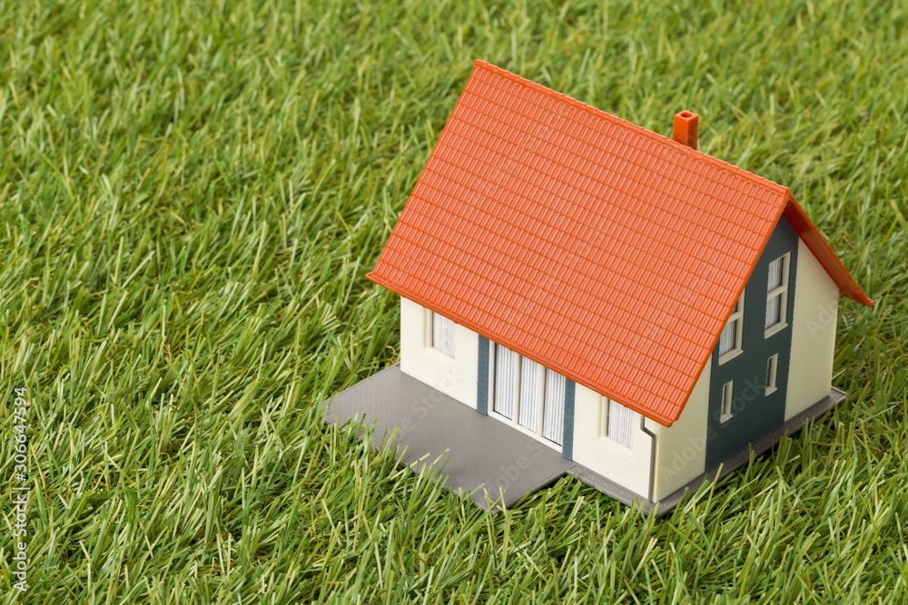 Miniature house model on green grass lawn background - house building or buying concept Miniature house model on green grass lawn background - house building or buying concept