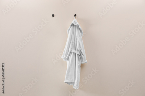 Soft comfortable bathrobe hanging on beige wall