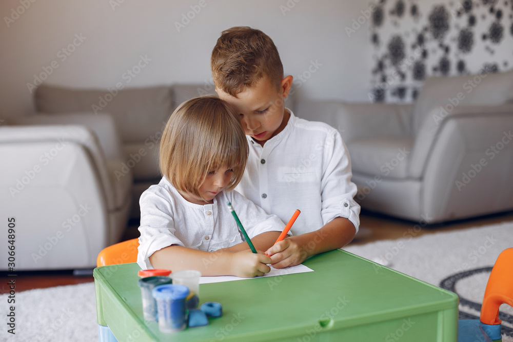 Brother and sister in a playing room. Children drawing at the table Brother and sister in a playing room. Children drawing at the table