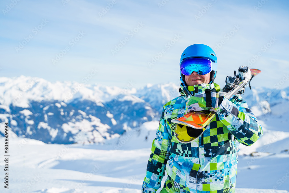 Portrait of happy sports man in helmet with snowboard standing on snow resort .