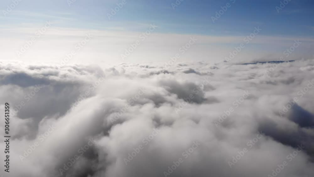 Aerial pan over thick fluffy cloudscape to distant mountains. Wide Aerial pan over thick fluffy cloudscape to distant mountains. Wide