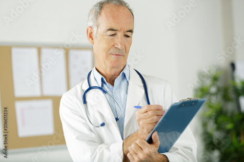 senior doctor writing recipe on the table with documents