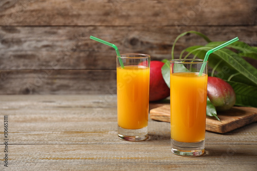 Fresh delicious mango drink on wooden table. Space for text