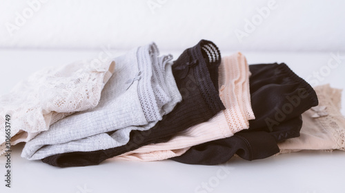 Stack of different women's panties lying on a white table in beige natural colour. Women underwear background. Copy space