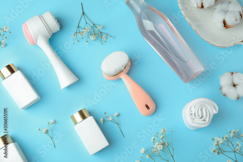 Flat lay composition with face cleansing brushes on light blue background. Cosmetic accessories