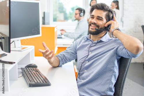 Smiling sales agent with headset talking to client in call centre