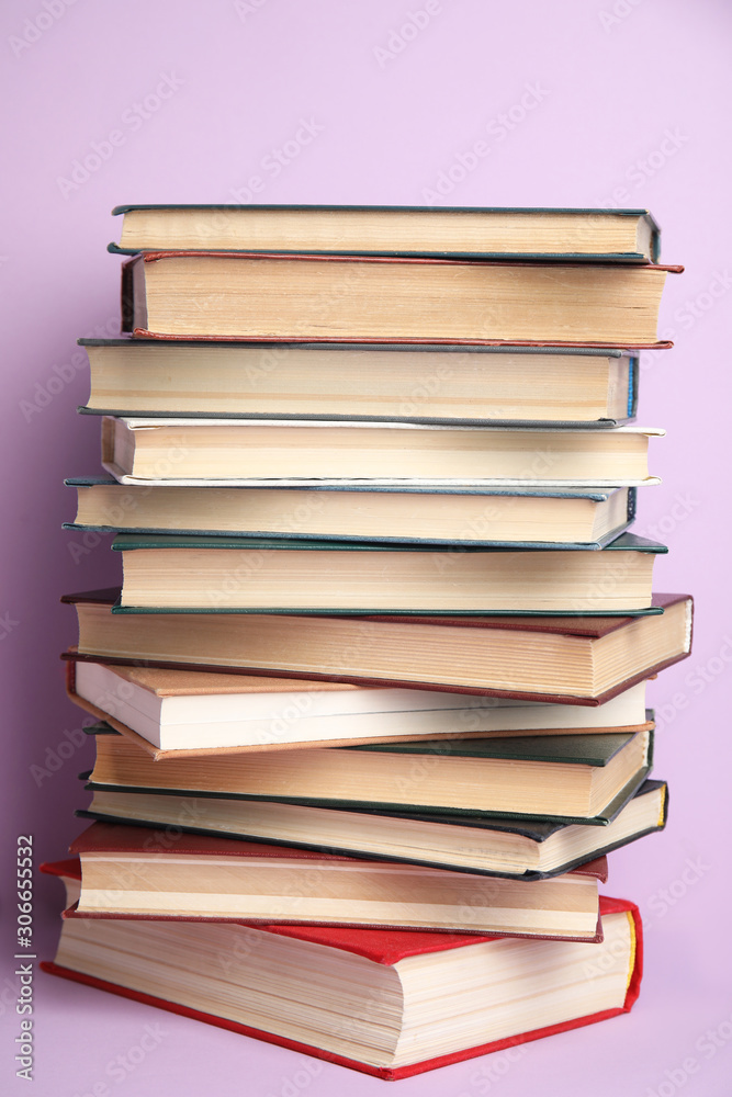 Stack of different hardcover books on violet background Stack of different hardcover books on violet background