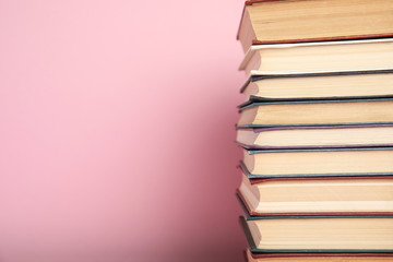 Stack of hardcover books on pink background. Space for text
