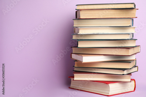 Stack of hardcover books on violet background. Space for text