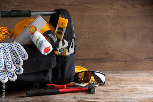 Photography Black bag with construction tools on wooden table. Space for text
