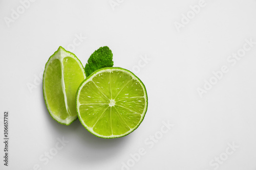 Cut fresh juicy lime and mint on white background, top view