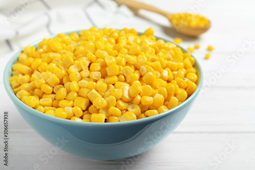 Delicious canned corn in bowl on white wooden table, closeup