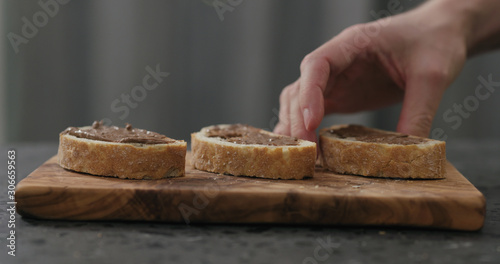 man take ciabatta slice with chocolate nut butter on olive board