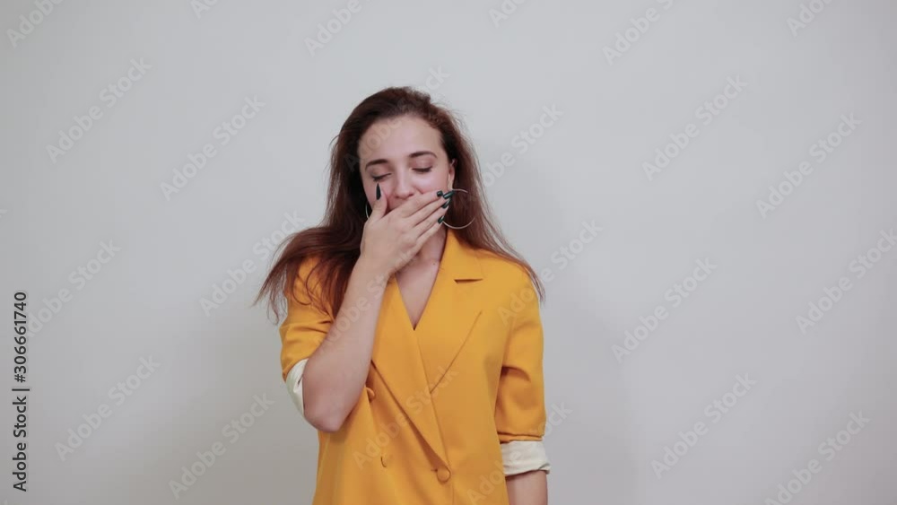 Drowsy young woman in yellow jacket isolated on gray background in studio doing sleep gesture, looking happy. People sincere emotions, lifestyle concept. Drowsy young woman in yellow jacket isolated on gray background in studio doing sleep gesture, looking happy. People sincere emotions, lifestyle concept.