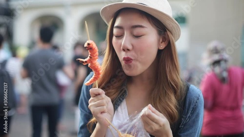 Asian Young woman  Eating Traditional Asian Street Food  at   Market Bangkok city.Close up of pretty woman eating thai street food .