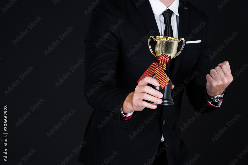 Confident businessman in black suit with Champion Cup