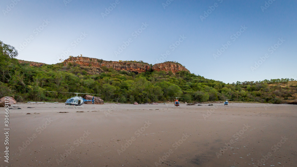 Tourists from a luxury expedition cruise ship board helicopters on a remote beach on Naturalist Island in the Kimberley for a sightseeing flight over Prince Frederick Harbour