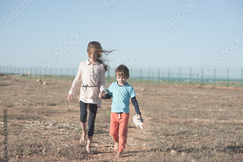 deportation concept of refugee orphan family boy and girl holding hands walking in hot desert near state border seeking for political asylum
