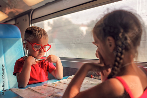 Canvas Print Little boy with his sister discussing their vacation during travelling by train