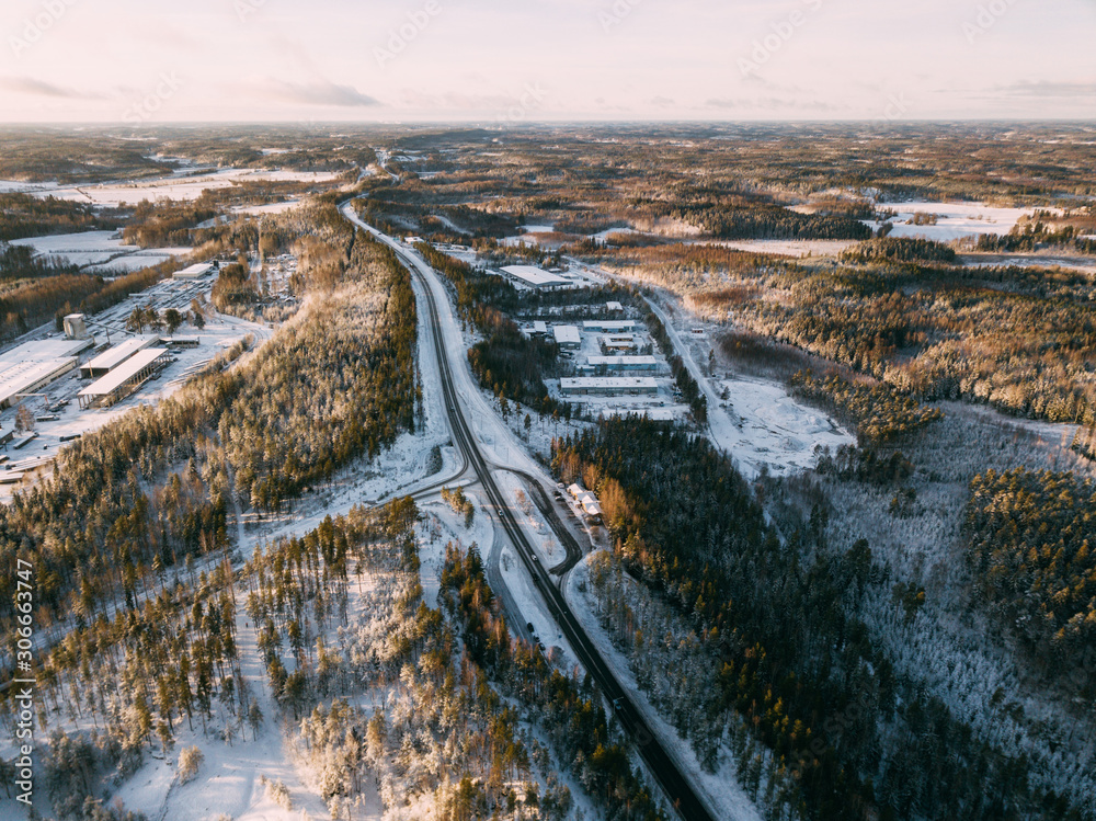 Aerial view on the road and forest at the winter time. Natural winter landscape from air. Landscape in Finland from drone