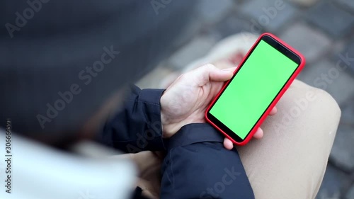 Closeup of man hand using green screen smartphone mobile outside. Winter holidays. Greeting friends. Happy New Year. Christmas traveling weekend. Chromakey mock-up. Swapping display. App notification