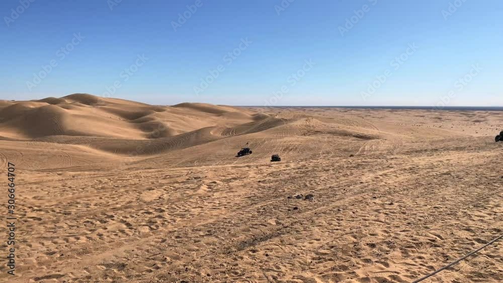 Pan view of ATVs driving on sand dunes, on a sunny day, in USA Pan view of ATVs driving on sand dunes, on a sunny day, in USA