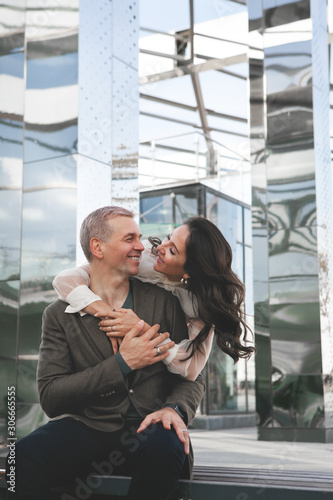 Couple in love. Stunning sensual outdoor portrait of woman hugging man on date. Happy couple dating on the street, glass business center on background